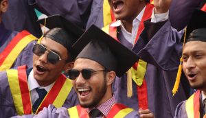 Group of diverse graduates celebrating with enthusiasm in convocation attire.